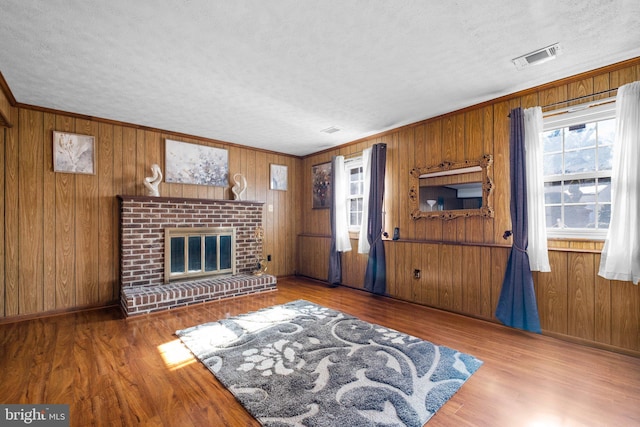 living room with hardwood / wood-style flooring, crown molding, wooden walls, and a fireplace