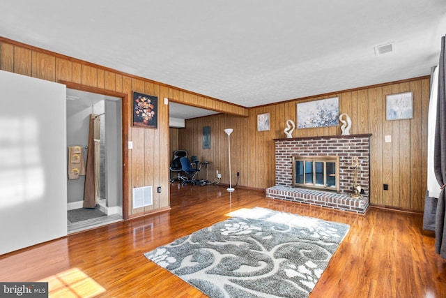 living room with hardwood / wood-style flooring, a brick fireplace, and wood walls