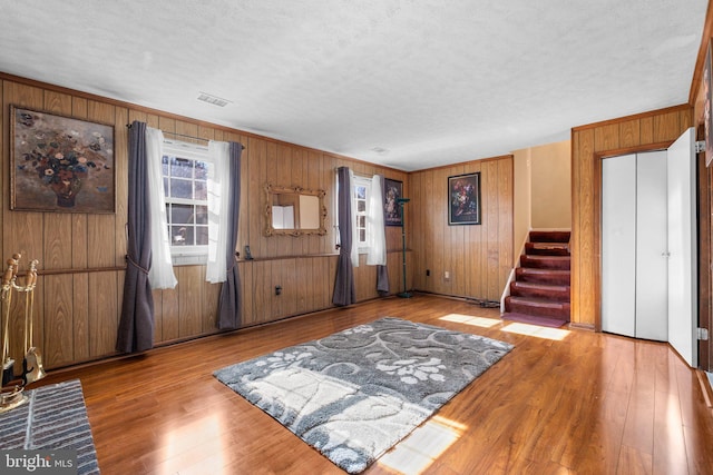 entrance foyer featuring wooden walls, a textured ceiling, and light wood-type flooring