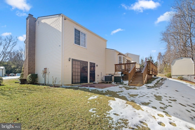 back of property with a wooden deck, central AC unit, and a lawn