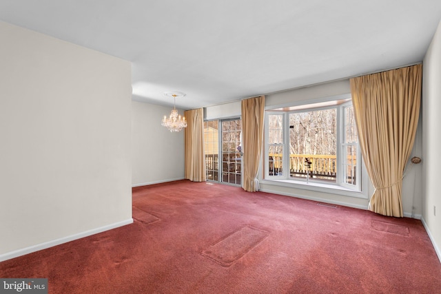 carpeted empty room with an inviting chandelier