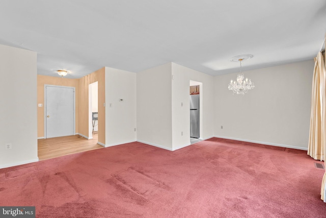 carpeted spare room with an inviting chandelier