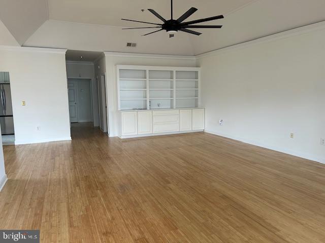 spare room featuring ceiling fan, built in features, light hardwood / wood-style floors, and ornamental molding