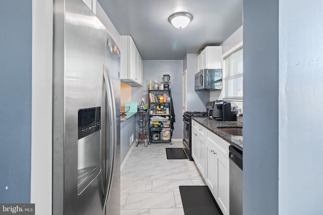 kitchen with white cabinets, sink, stainless steel appliances, and dark stone countertops