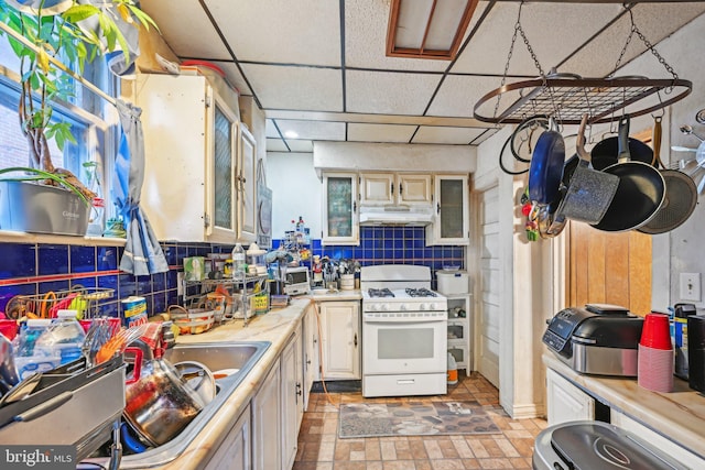 kitchen featuring decorative backsplash, a paneled ceiling, and white gas range