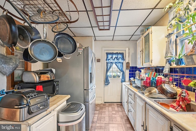 kitchen with a paneled ceiling, sink, and white cabinets