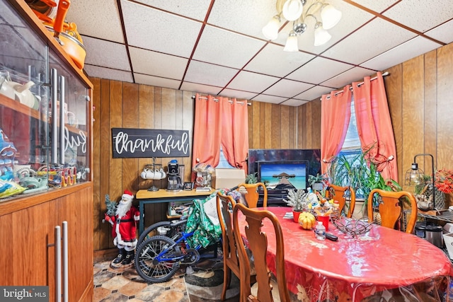 dining area featuring wooden walls and a drop ceiling