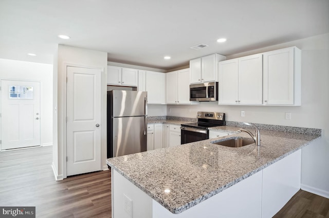 kitchen featuring sink, kitchen peninsula, wood-type flooring, white cabinets, and appliances with stainless steel finishes