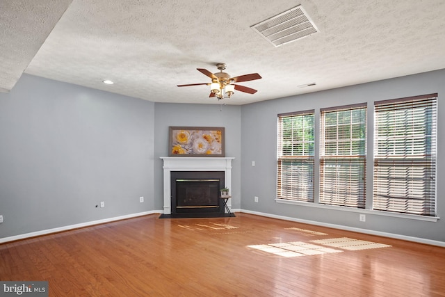 unfurnished living room with wood-type flooring, a textured ceiling, and ceiling fan