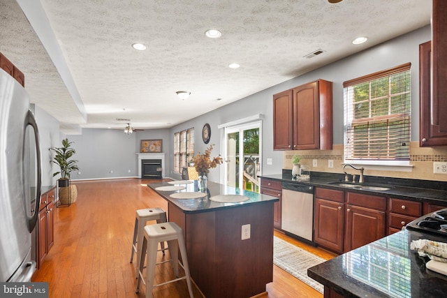 kitchen with a kitchen bar, appliances with stainless steel finishes, light wood-type flooring, sink, and a center island