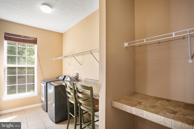 laundry area featuring washer and clothes dryer, light tile patterned floors, and a textured ceiling