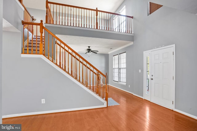 foyer featuring ceiling fan, a towering ceiling, and hardwood / wood-style flooring