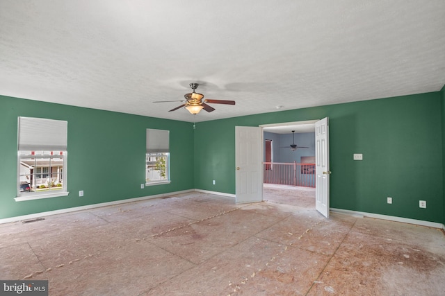 unfurnished room with ceiling fan and a textured ceiling