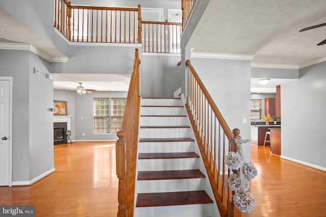 stairs featuring a textured ceiling, ceiling fan, wood-type flooring, and crown molding