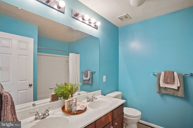 full bathroom with vanity, toilet, a textured ceiling, and shower / tub combo