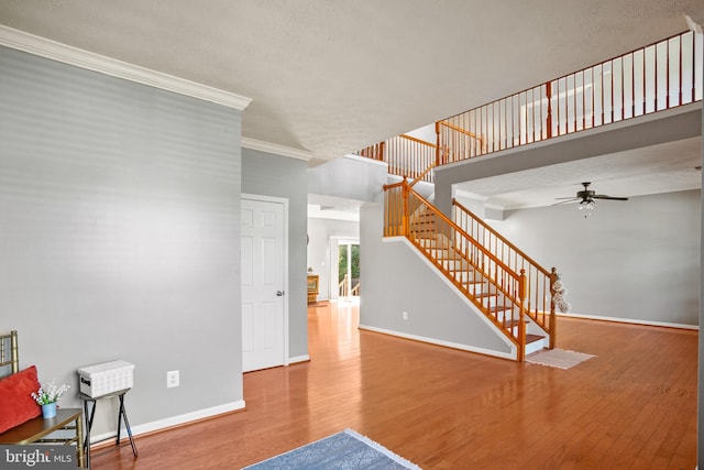 interior space with wood-type flooring, a textured ceiling, ceiling fan, and crown molding