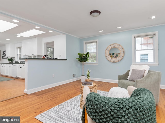 sitting room with light hardwood / wood-style flooring, plenty of natural light, and ornamental molding