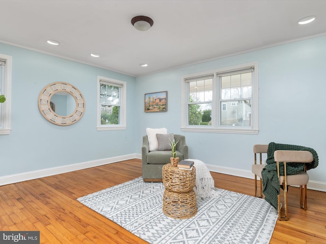 living area featuring plenty of natural light, light hardwood / wood-style floors, and ornamental molding