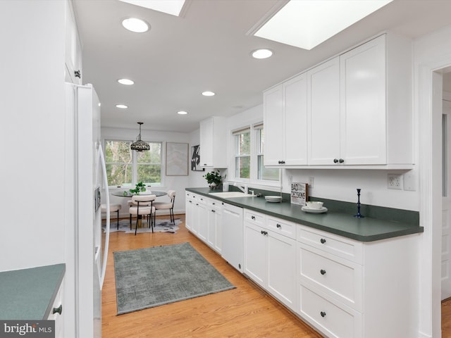 kitchen featuring a skylight, sink, light hardwood / wood-style flooring, white appliances, and white cabinets