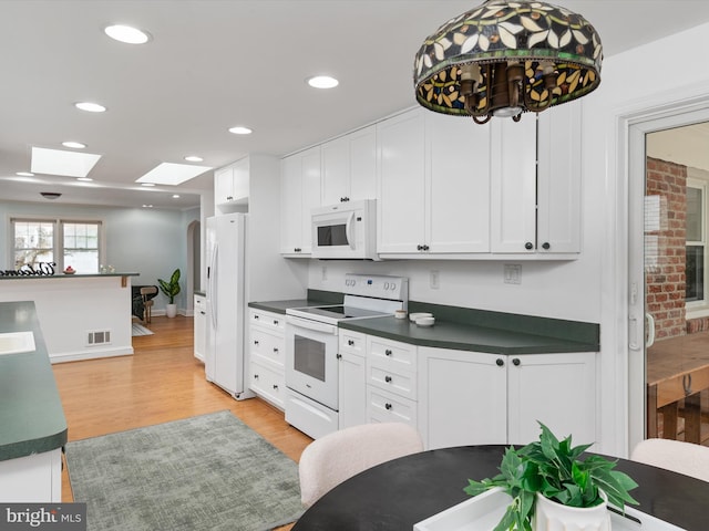 kitchen with white appliances, white cabinetry, light hardwood / wood-style flooring, and a skylight