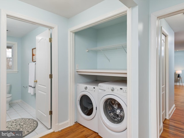 laundry area featuring washer and clothes dryer and light hardwood / wood-style floors