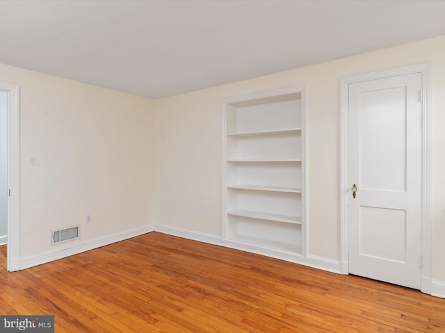 unfurnished room with built in features and light wood-type flooring