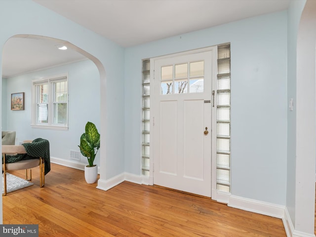 foyer entrance with crown molding and light wood-type flooring