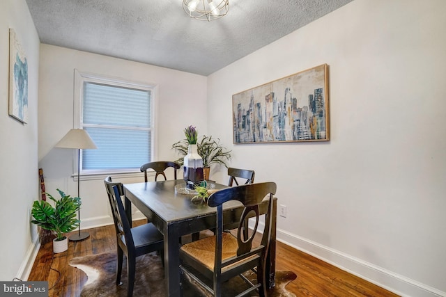 dining area with a textured ceiling and dark hardwood / wood-style flooring