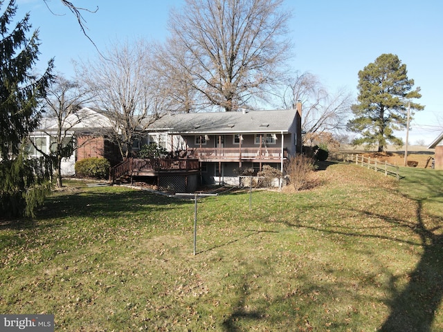 back of property with a deck and a yard