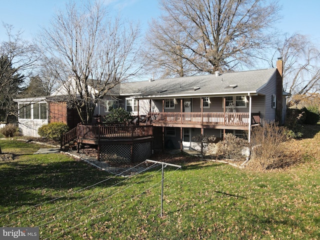 rear view of house with a lawn, a wooden deck, and a sunroom