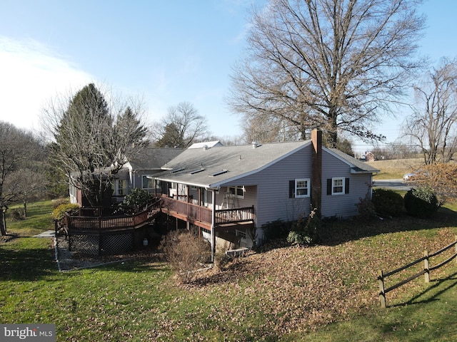 back of property featuring a lawn and a wooden deck