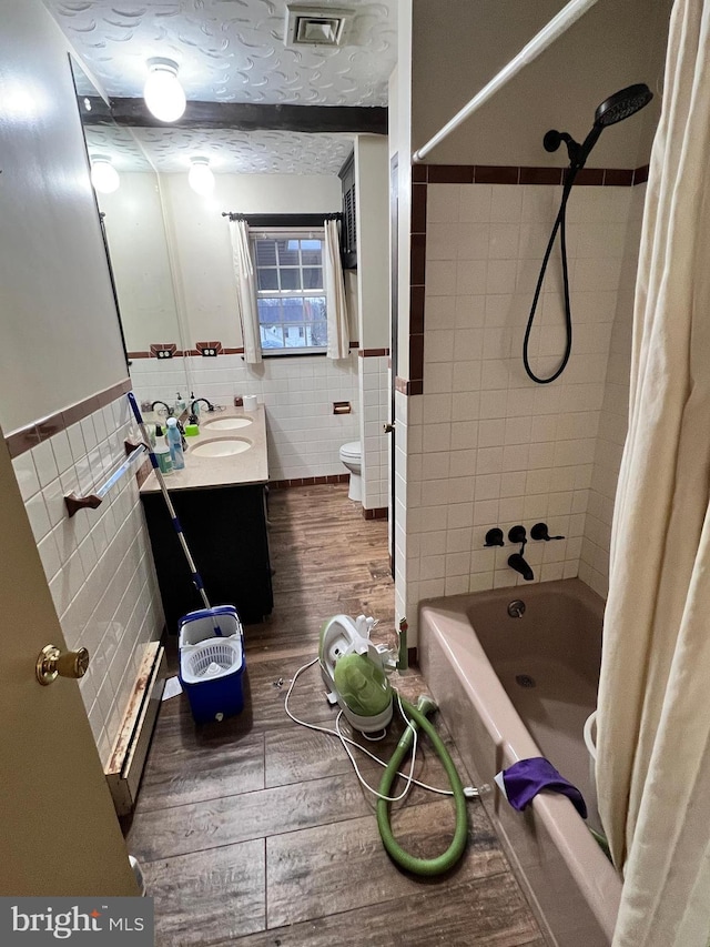 full bathroom featuring shower / bath combination with curtain, a textured ceiling, wood-type flooring, vanity, and tile walls