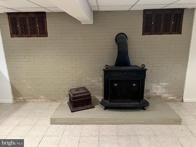 interior details with a paneled ceiling and a wood stove