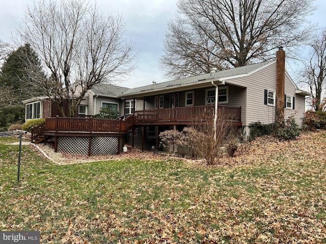 rear view of house with a wooden deck and a lawn