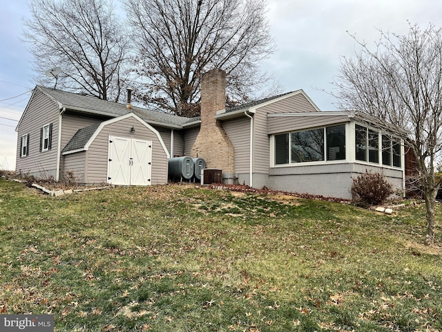 view of home's exterior with a sunroom, a storage unit, and a yard