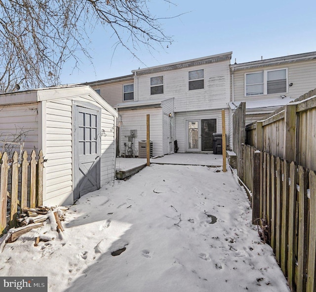 snow covered property with a storage unit and central AC