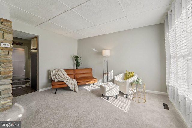 sitting room featuring a drop ceiling and carpet flooring