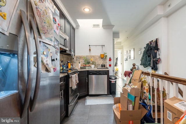 kitchen featuring tasteful backsplash, light stone countertops, dark tile patterned flooring, and appliances with stainless steel finishes