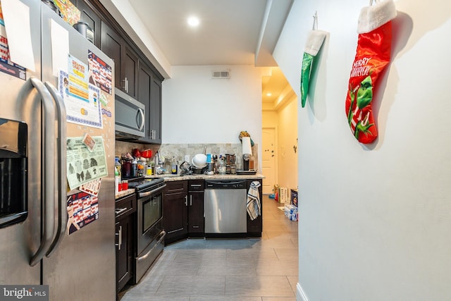 kitchen featuring tasteful backsplash, light stone countertops, dark brown cabinets, and appliances with stainless steel finishes