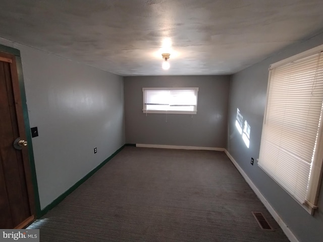 unfurnished room featuring dark colored carpet