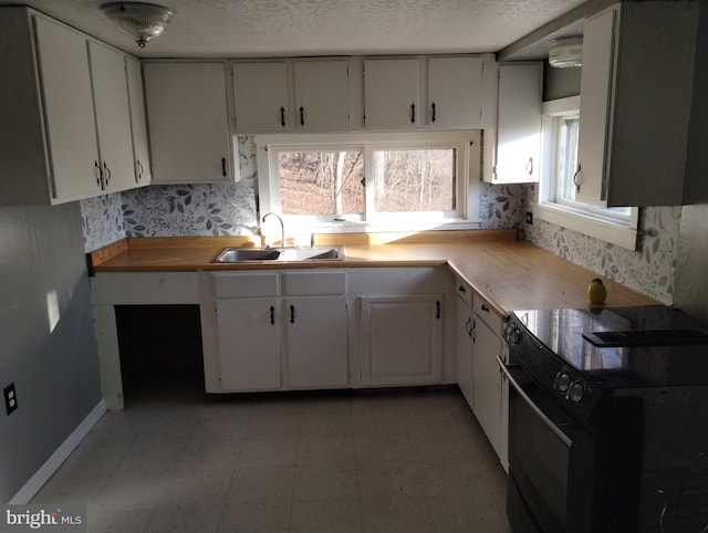 kitchen with white cabinetry, sink, electric range, and a textured ceiling