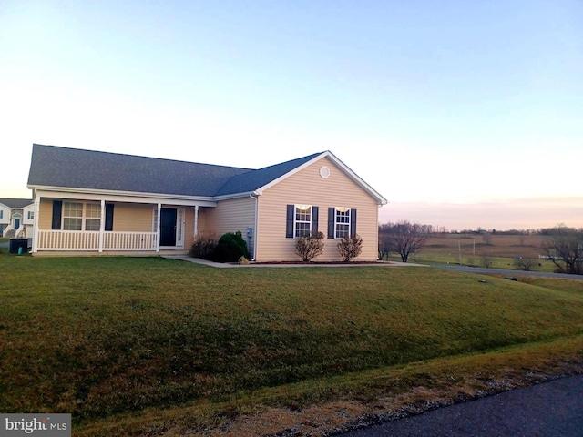 ranch-style home with covered porch and a lawn