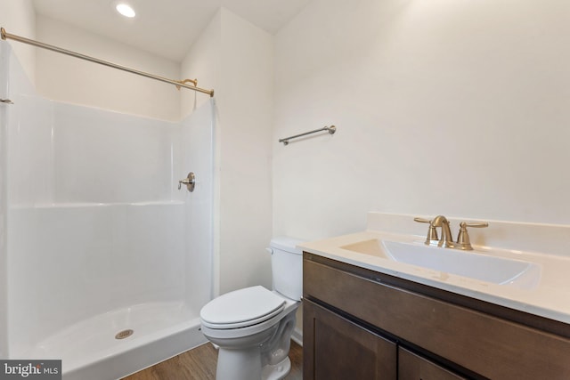 bathroom featuring wood-type flooring, vanity, toilet, and walk in shower