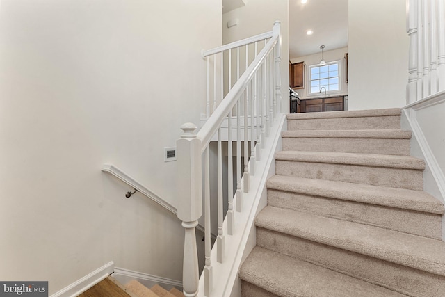 staircase with hardwood / wood-style floors and sink