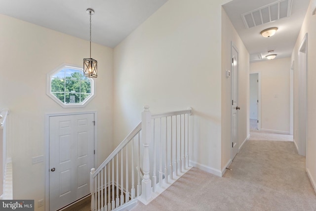 carpeted entryway with a notable chandelier