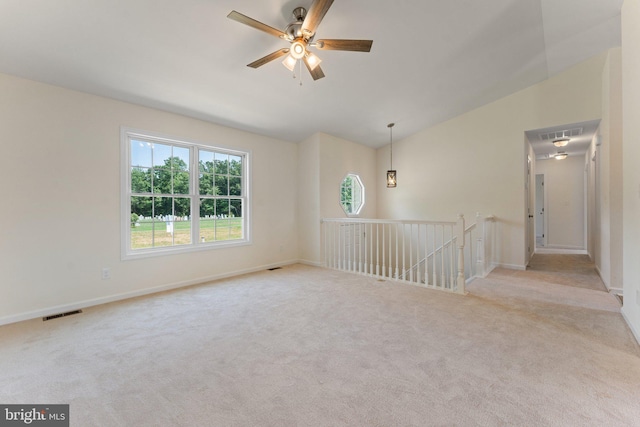 carpeted spare room featuring vaulted ceiling and ceiling fan