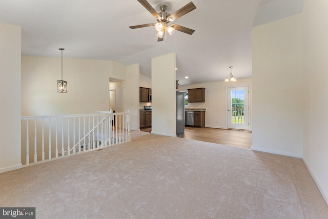 unfurnished living room with ceiling fan with notable chandelier, light colored carpet, and vaulted ceiling