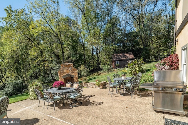 view of patio with area for grilling and an outdoor stone fireplace