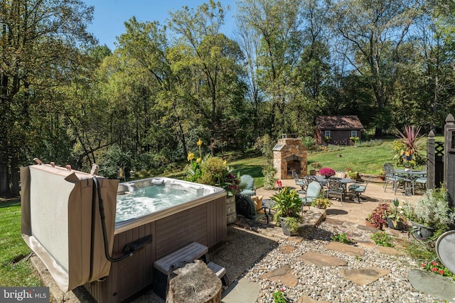 view of patio with a hot tub, an outdoor stone fireplace, and a storage unit