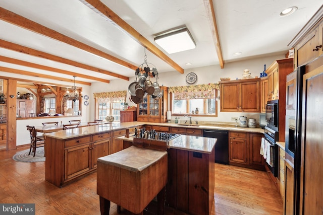 kitchen with black appliances, a kitchen island, beamed ceiling, and kitchen peninsula